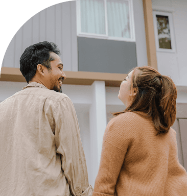 A group of people at an event are laughing and cheering, with one man enthusiastically greeting a seated couple in the front row.