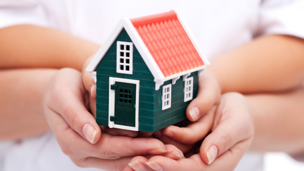 Hands on a toy house.