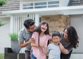 Couple laughing with kids in front yard of home