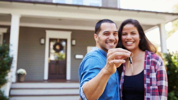 A couple holding house keys in front of their new home