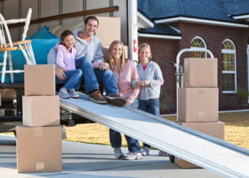 A family smiling in a moving truck with moving boxes