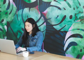 Woman using laptop behind a bright mural
