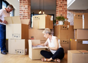 A couple packs up moving boxes in their home