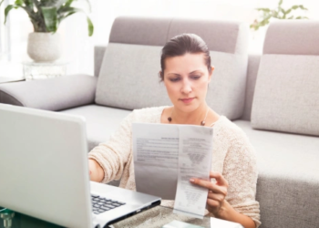 A woman looks at financial statements at a computer desk.