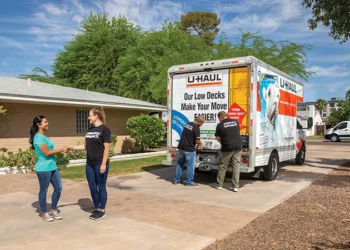 A customer shakes hands with a Moving Help Service Provider after completing a successful job of loading the customer’s belongings into a U-Haul truck rental. Two labor-only providers in the background close the U-Haul truck rental.