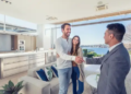 A couple shaking hands with a real estate agent in a home.