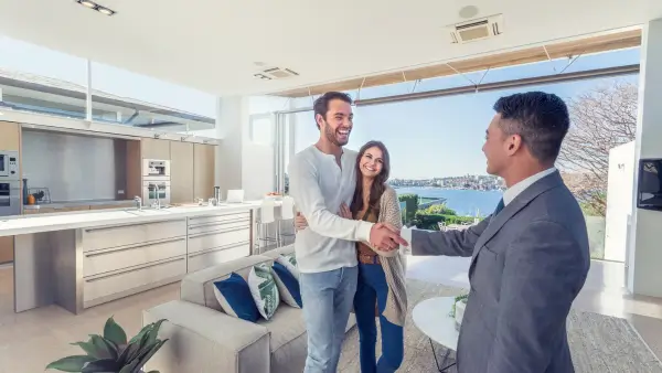 A couple shaking hands with a real estate agent in a home.