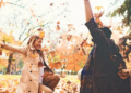 Two people surrounded by orange, fall leaves.