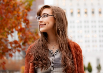 Woman with long hair and glasses walking outdoors in autumn