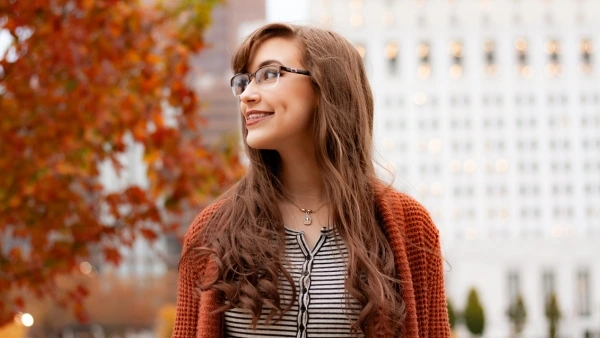 Woman with long hair and glasses walking outdoors in autumn