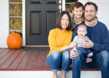 A family sitting on the front porch of their home.