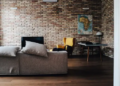 A living room featuring brick walls, 2 sofas, a TV and a table.