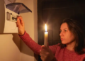 A woman holding a candle in the dark during a power outage