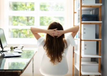 A person sitting at a home office, looking out a window.