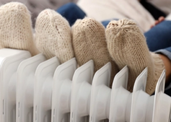 2 pairs of feet being warmed up by a heater.