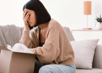 A person sitting on a couch, with their head in their hands.