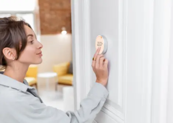 A person adjusting their smart thermostat.