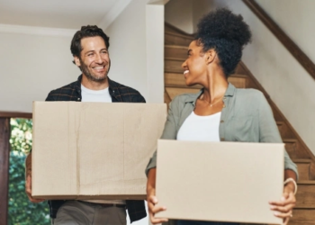 A couple holding moving boxes.