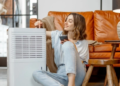 A woman sitting next to an air purifier